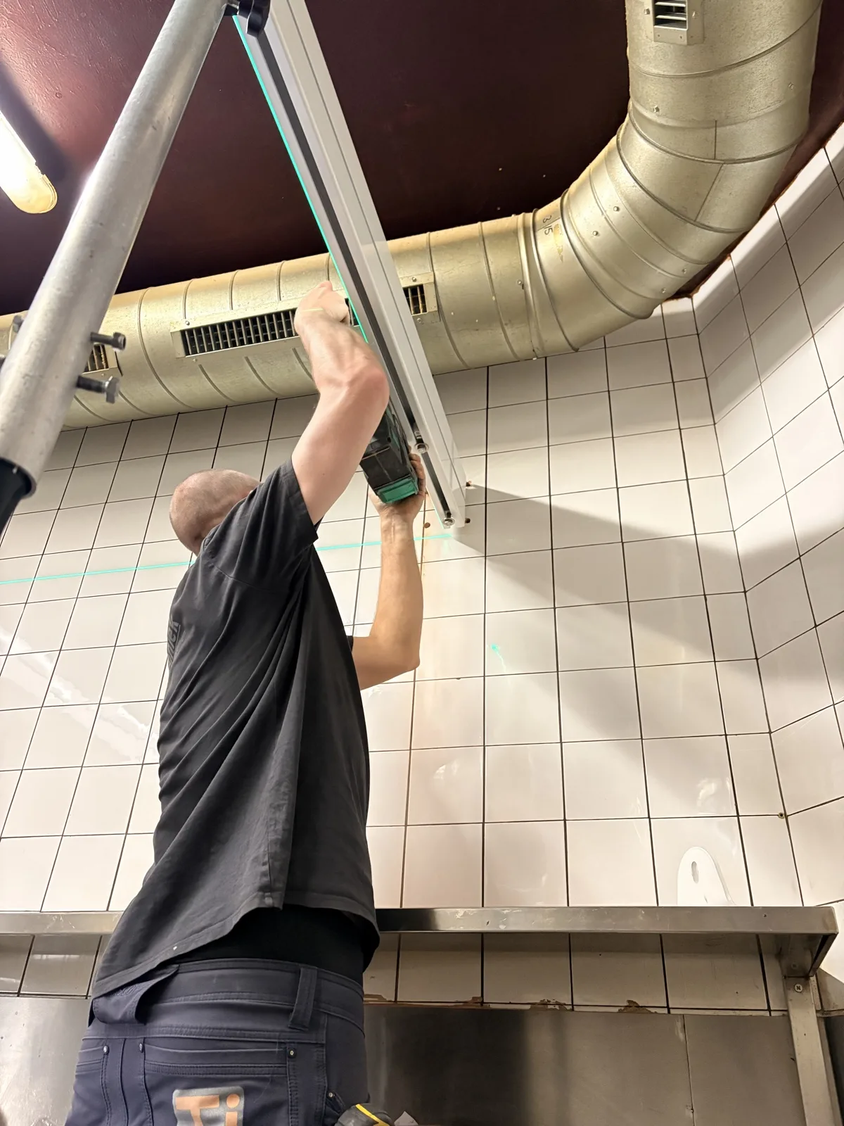 Monteur bevestigt het railsysteem aan het keukenplafond