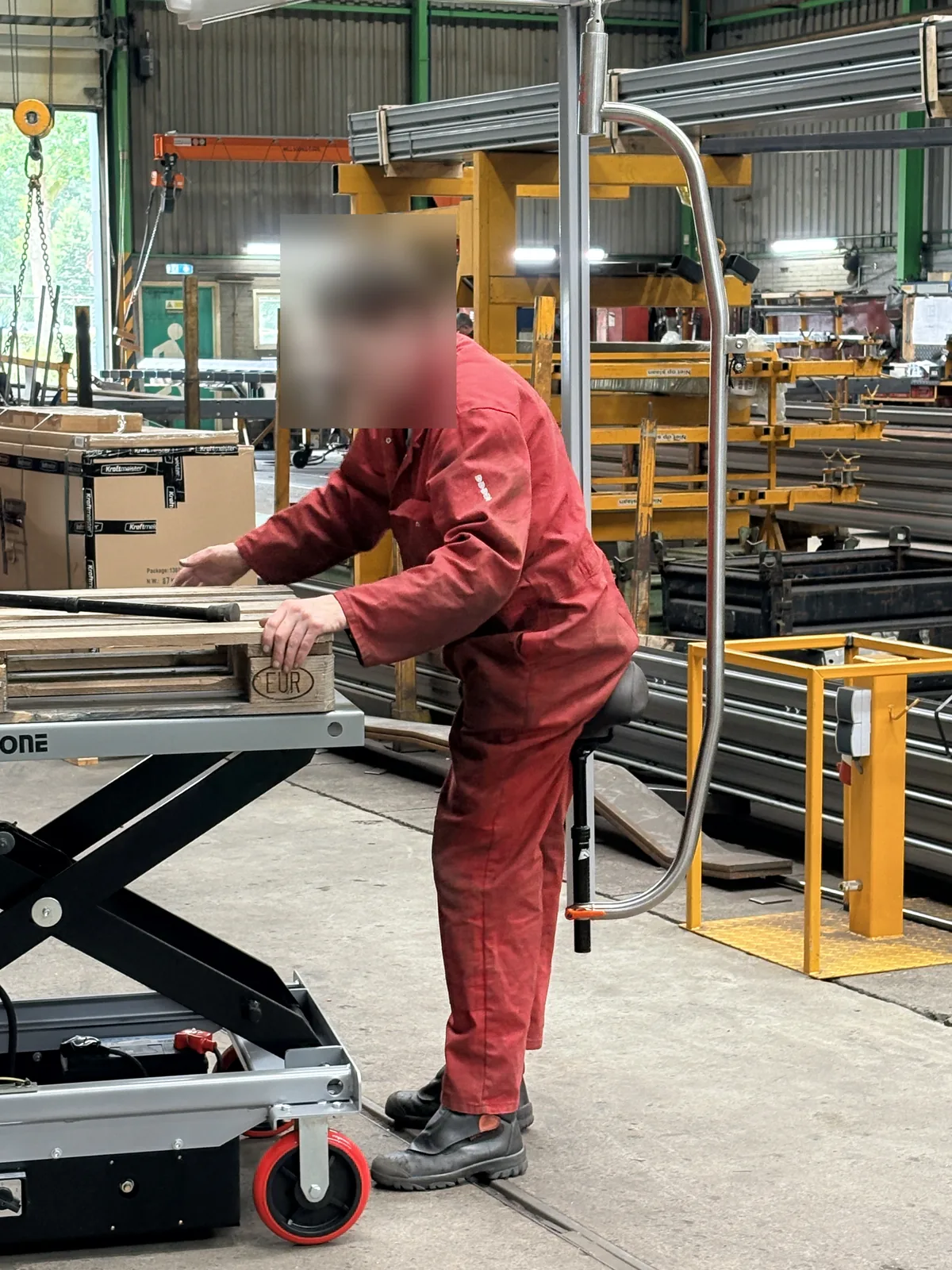 Medewerker legt materiaal klaar op een hoog-laag werkbank, steunend op het zadel