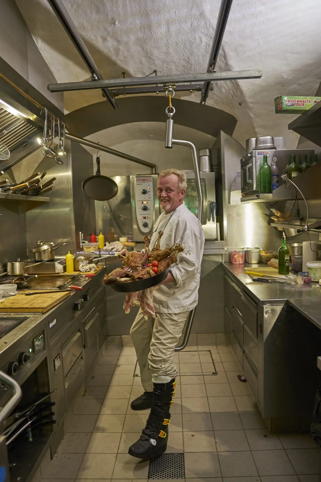 Kok met een beenorthese staat in zijn keuken, ondersteund door de mobiliteitsbeugel
